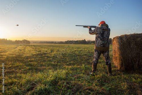 Hunter with shotgun rifle aimng at pheasant.