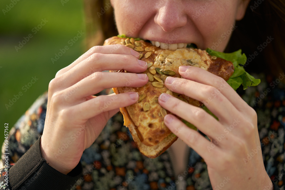 A young girl eats a fresh sandwich, a clear and sunny day. A young girl eats a fresh sandwich, a clear and sunny day.