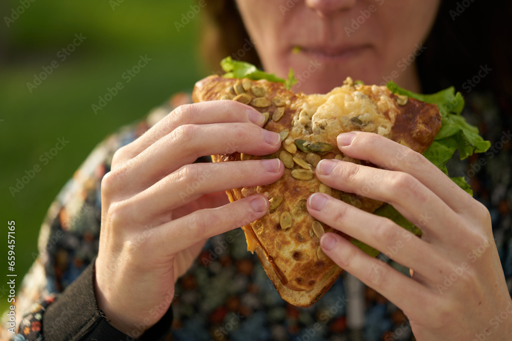 A young girl eats a fresh sandwich, a clear and sunny day. A young girl eats a fresh sandwich, a clear and sunny day.
