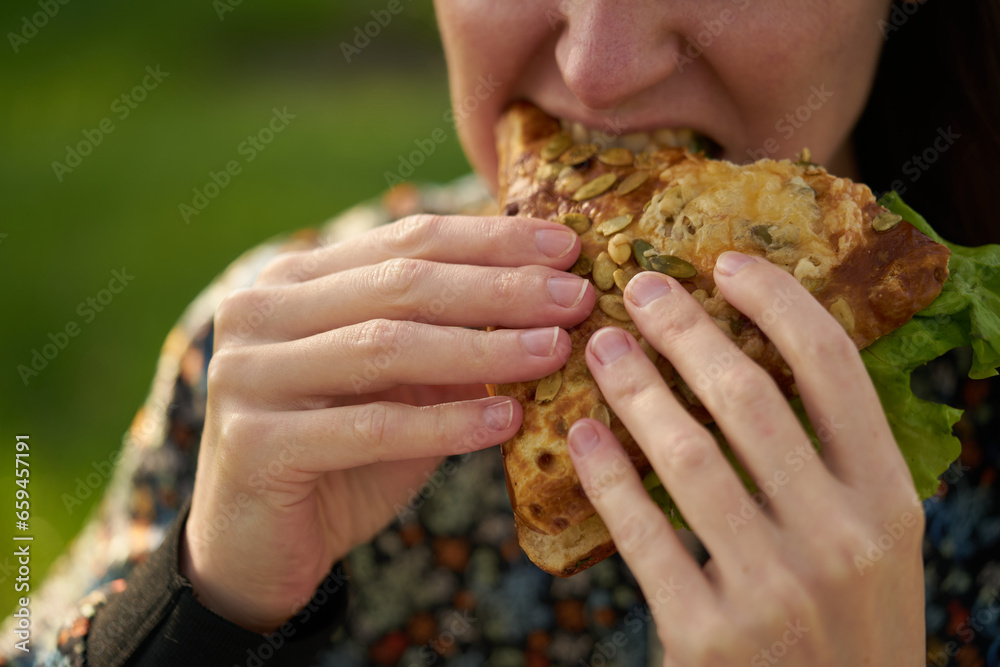 A young girl eats a fresh sandwich, a clear and sunny day. A young girl eats a fresh sandwich, a clear and sunny day.