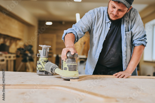 Carpenter works with wood in carpentry workshop. Man doing woodwork professionally