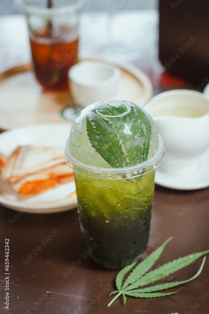 Cannabis Lime Soda Cooling drinks with cannabis as an ingredient are placed on a classic wooden table in glasses decorated with beautiful cannabis leaves. Recreational cannabis concept.