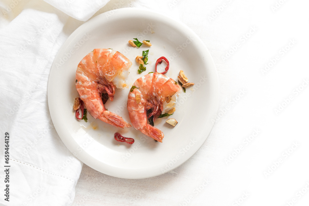 Two fried tiger prawns or shrimps with red chili pepper, garlic and herbs on a white plate, spicy seafood meal, high angle view from above, copy space Two fried tiger prawns or shrimps with red chili pepper, garlic and herbs on a white plate, spicy seafood meal, high angle view from above, copy space