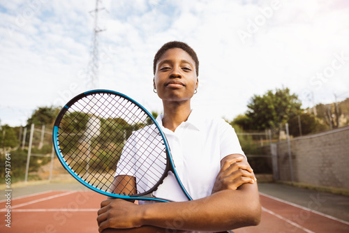 Portrait of a young beautiful women with tennis clothes and racket in a tennis court ready to play a game. © Jordi Salas