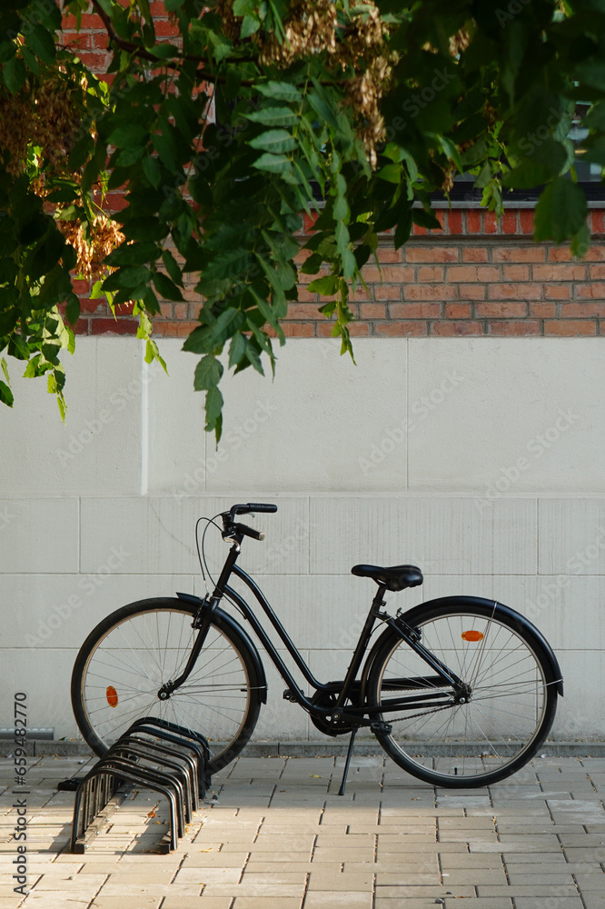 Black retro bicycle parked on bike rack in front of brick wall in Bucharest