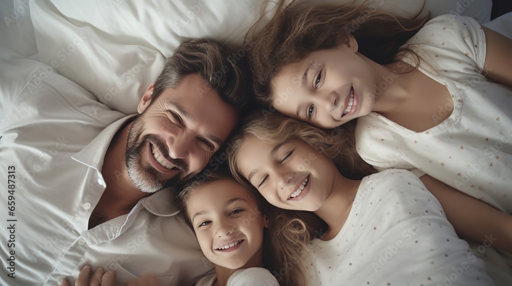 Family and love: top view, happy family teasing each other in bed, parents and children, warm white bedroom, hugs Family and love: top view, happy family teasing each other in bed, parents and children, warm white bedroom, hugs