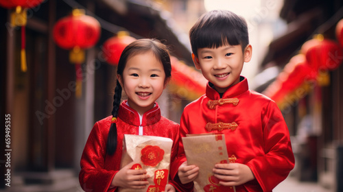 Cute Chinese girl and boy wearing red Chinese clothes holding red envelopes celebrate the Chinese New Year in an old China town