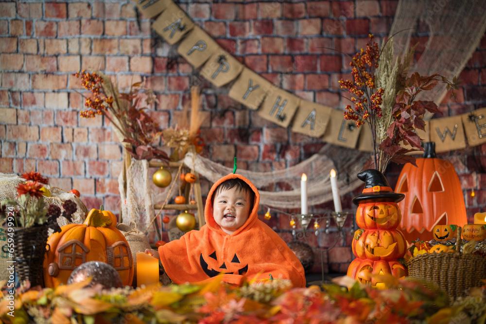 10月にハロウィンのフォトセットに囲まれて楽しそうな笑顔を見せる生後11か月の赤ちゃん