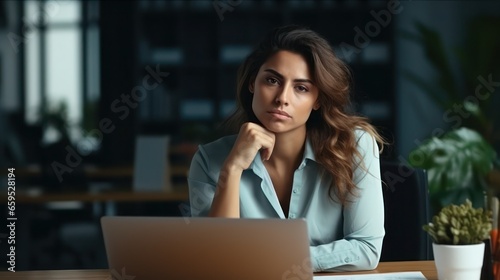 Serious young businesswoman sitting at desk in office