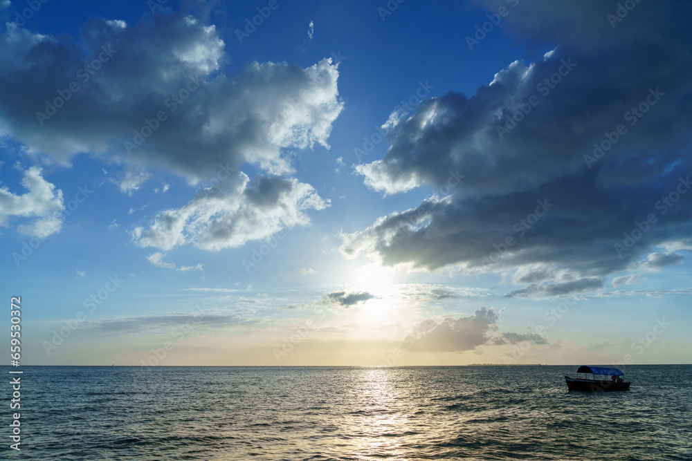 sunset over a seascape with calm ocean water and clouded blue sky