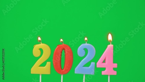 Happy New Year 2024, colorful candle number 2024 shape for new year celebrate party was lit. flame at candlewick sway and blown out isolated on green screen background, horizontal frame rate 60P photo