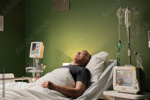 Elderly person sleeping in a hospital room with a breathing tube and a finger gadget