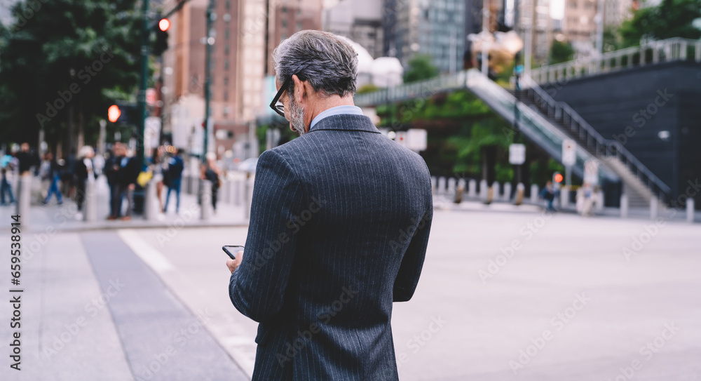 Elegant middle aged male looking at smartphone on urban background. Elegant middle aged male looking at smartphone on urban background.