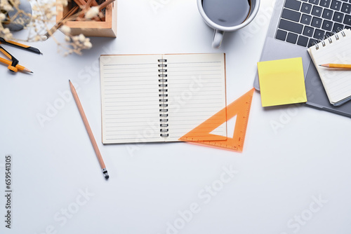 White office desk with laptop  cup of coffee  notepad and stationery. Top view with space for text