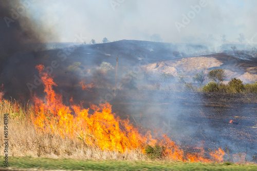 Big Fire in the fields with bright fire and smoke on a dry summer day. Emergency and fire hazard © Natalia