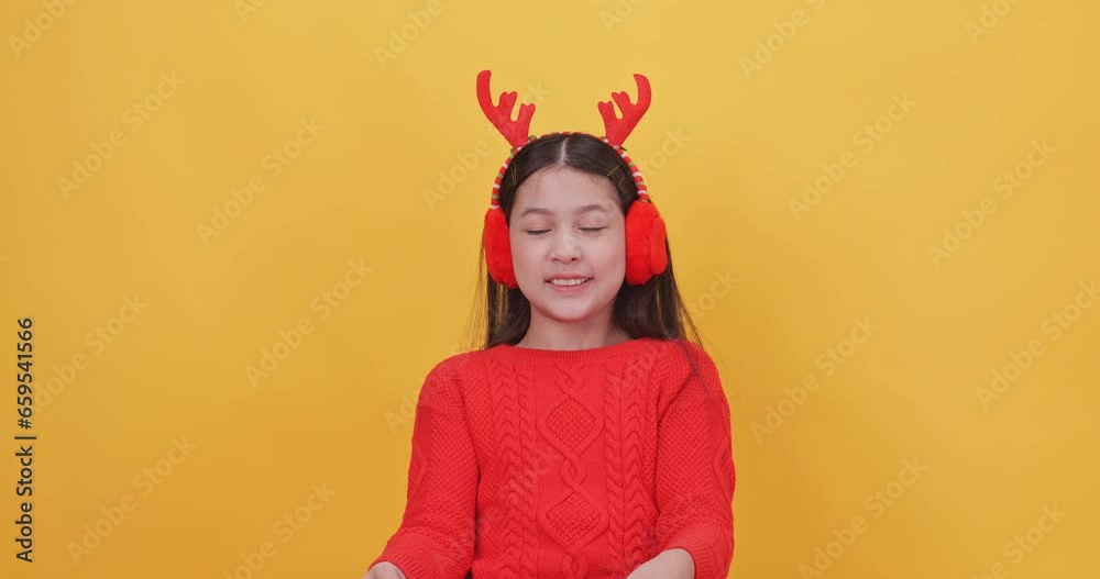 Cute little girl wearing a Christmas costume holding a big gift box on a yellow background. Cute little girl wearing a Christmas costume holding a big gift box on a yellow background.