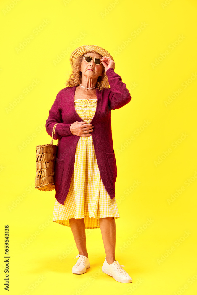 Full-length of beautiful senior woman, grandmother in comfortable clothes posing over yellow studio background. Concept of human emotions, fashion, elderly people, lifestyle, creativity. Ad Full-length of beautiful senior woman, grandmother in comfortable clothes posing over yellow studio background. Concept of human emotions, fashion, elderly people, lifestyle, creativity. Ad
