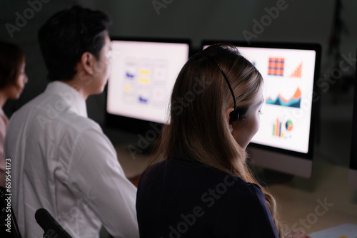 Group of broker international stock traders wearing headset working actively at night in office, Concept of customer support agent provide service on telephone.