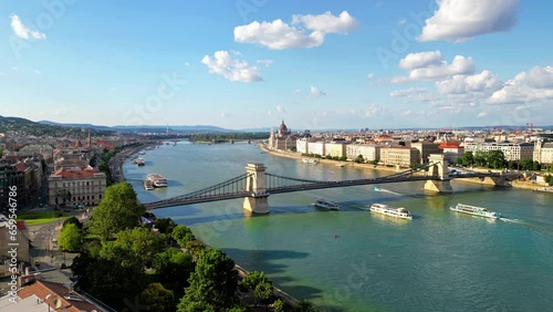 Aerial drone view of Budapest, Hungary. Chain Bridge over the Danube river with floating boats, Hungarian Parliament in the distance, a lot of greenery and classic buildings