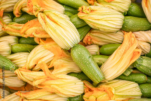 Flowers of zucchini and zucchini closeup on the farm market stall. Food background.