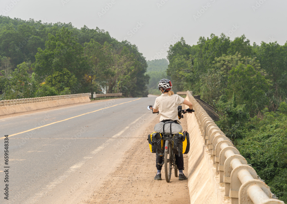 Nomadic woman travels on her bicycle loaded with bags Nomadic woman travels on her bicycle loaded with bags