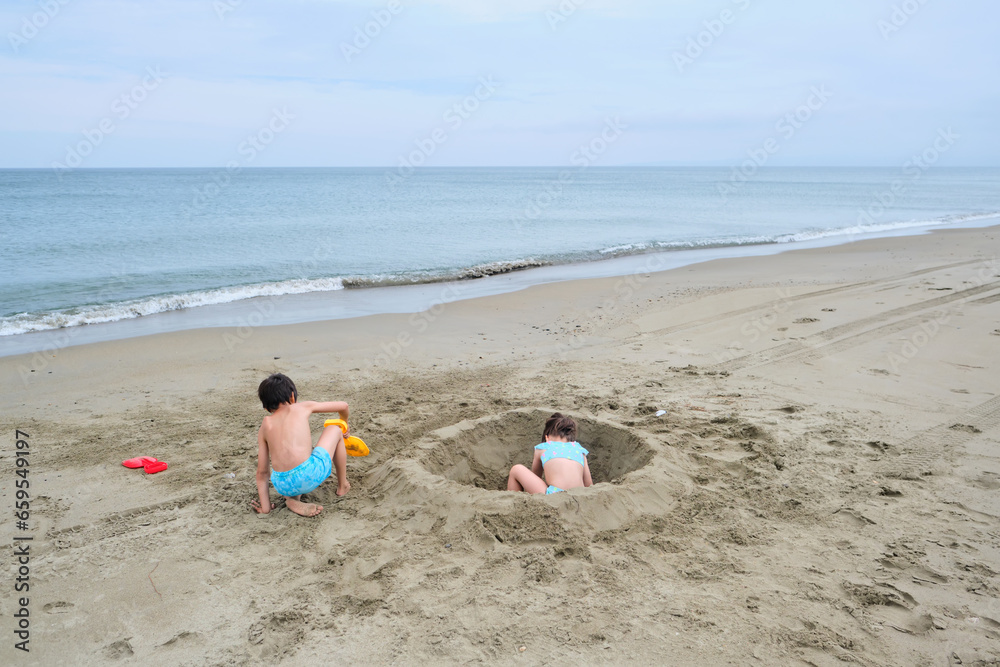 Children dig a hole in the sand on the seashore. Children dig a hole in the sand on the seashore.