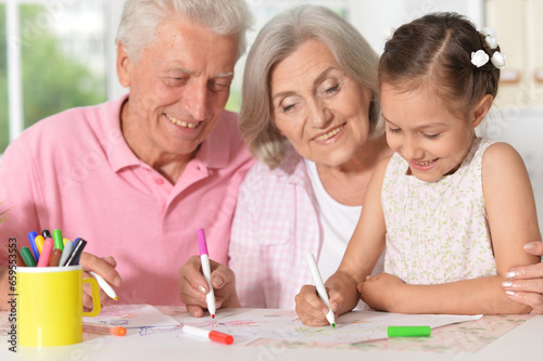 girl with grandparents drawing at the table