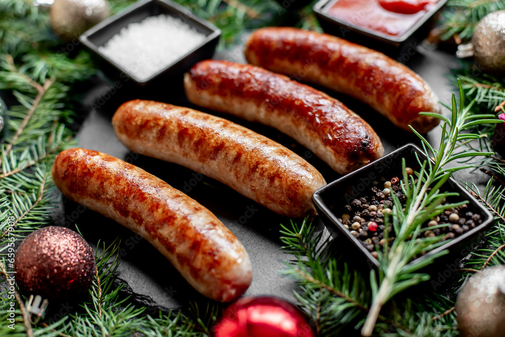 Christmas grilled sausages with spices on a stone background with Christmas trees and Christmas decorations, gifts  - obrazy, fototapety, plakaty 
