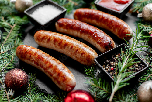 Christmas grilled sausages with spices on a stone background with Christmas trees and Christmas decorations, gifts 
