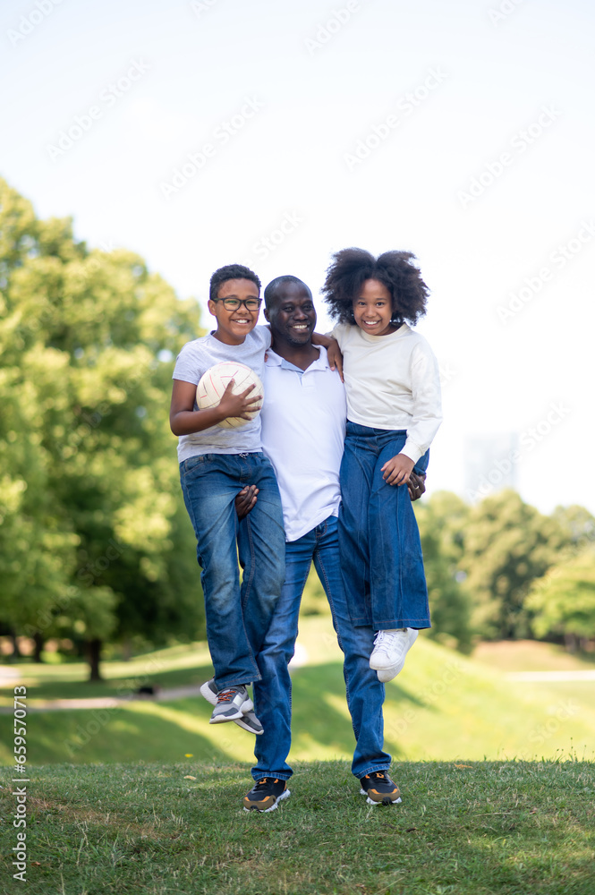 Dad and two kids looking happy while spending time in the park together Dad and two kids looking happy while spending time in the park together