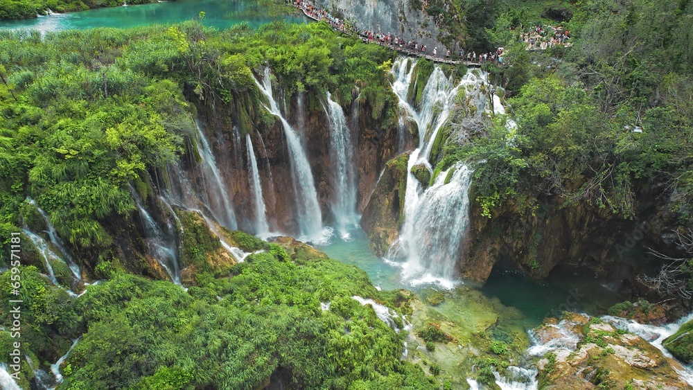 Long queue of people hiking on narrow path in Plitvice Lakes National Park Croatia. Mountain landscape with streams of water and waterfalls. Long queue of people hiking on narrow path in Plitvice Lakes National Park Croatia. Mountain landscape with streams of water and waterfalls.