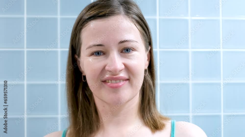 Young woman removes a sheet of moisturizing mask from her face on blue background. Young woman removes a sheet of moisturizing mask from her face on blue background.