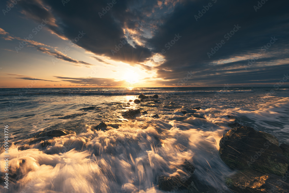 Golden splashing waves, rocky beach shore and sunrise sea horizon Golden splashing waves, rocky beach shore and sunrise sea horizon