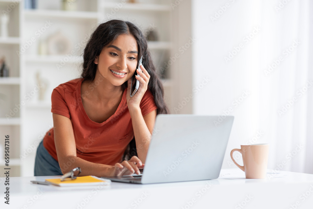 Energetic Millennial Eastern Woman Balancing Calls and Laptop Work Energetic Millennial Eastern Woman Balancing Calls and Laptop Work