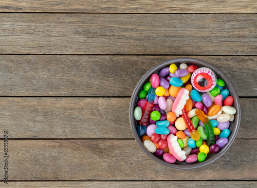 Assorted colorful candies on a bowl over wooden table with copy space