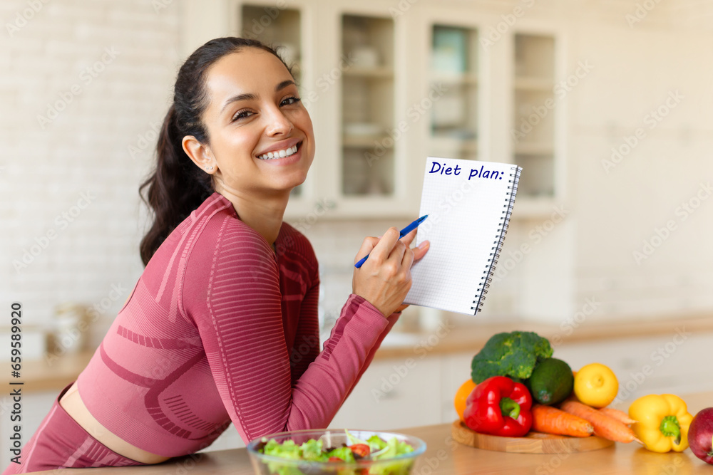 Smiling Fit Woman Posing With Diet Plan In Modern Kitchen - obrazy, fototapety, plakaty 