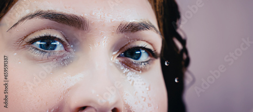 immagine primo piano con dettaglio viso di giovane donna bagnato da gocce d'acqua, scorcio occhi photo