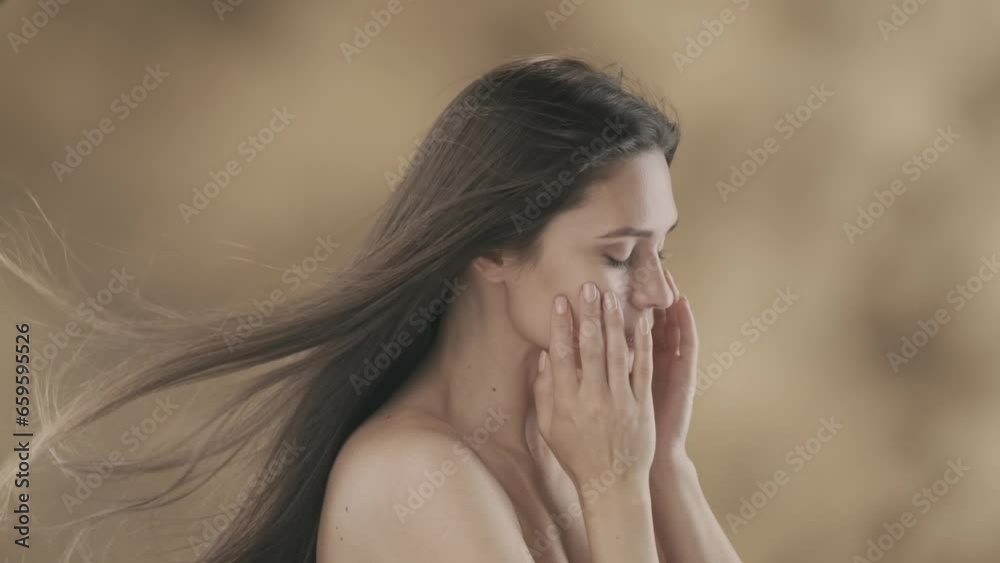 There is a middle-aged woman in the frame. She is standing sideways with her eyes closed. She runs her hands over her face and moves to her hair. She then opens her eyes, looks at the camera, smiles There is a middle-aged woman in the frame. She is standing sideways with her eyes closed. She runs her hands over her face and moves to her hair. She then opens her eyes, looks at the camera, smiles