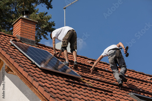 Workers prepare the roof for the installation of solar panels. Two men on the roof of a family house. Photovoltaic installation