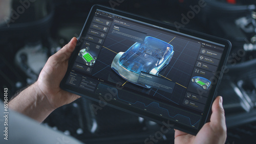 Automotive engineer holds digital tablet computer with simulation of real-time car diagnostics displayed on screen. 3D graphics visualization of professional software with 3D virtual electric vehicle