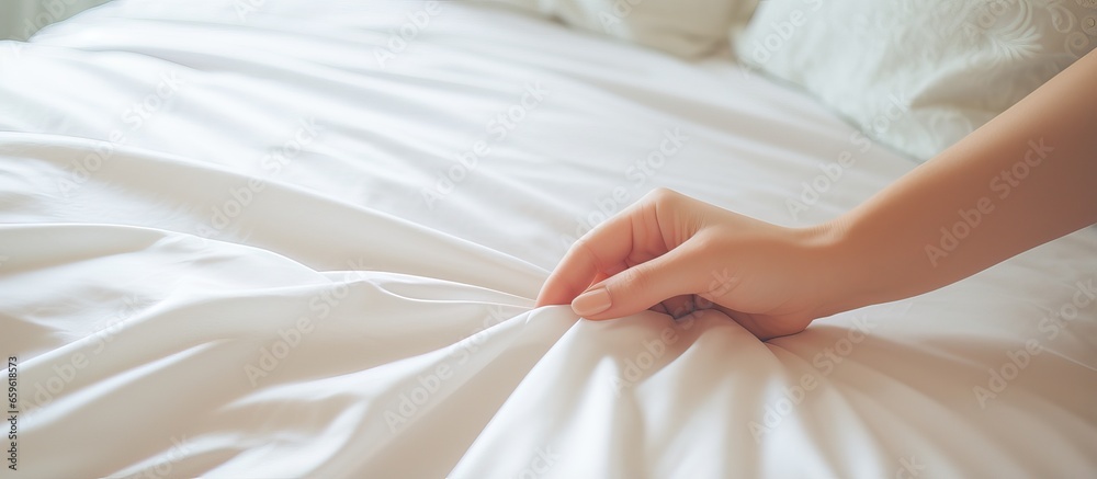 Woman arranging sheet on bed in bedroom or maid making bed in hotel room Woman arranging sheet on bed in bedroom or maid making bed in hotel room