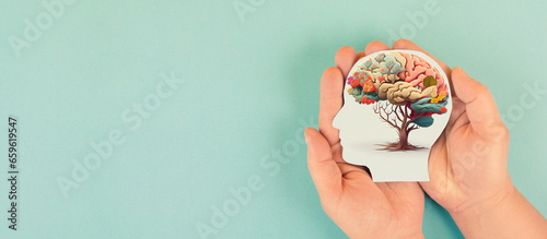 Hands holding paper head, human brain with flowers, self care and mental health concept, positive thinking, creative mind
