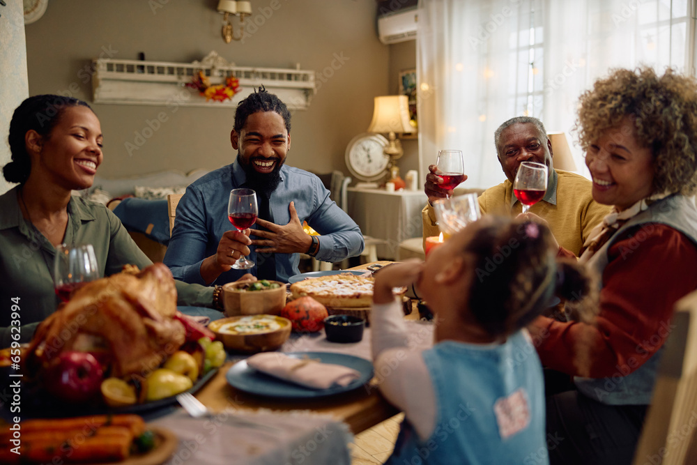 Cheerful black man has fun during family Thanksgiving meal at dining table.