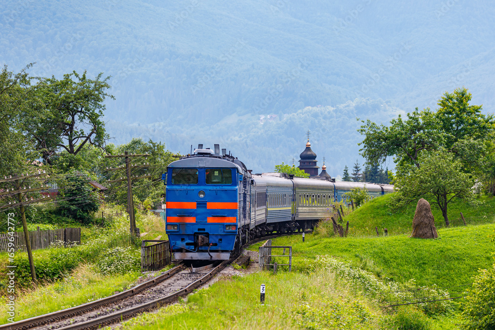 Naklejka premium Powerful diesel locomotive pulls passenger train. Railway in the mountains.