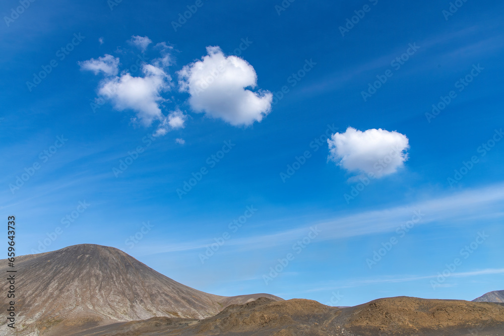 Panoramic view over volcanic landscape on Reykjanes Peninsula, Iceland, near sites of 2021 and 2022 eruptions near mountain Fagradalsfjall volcano area against a white clouded blue sky