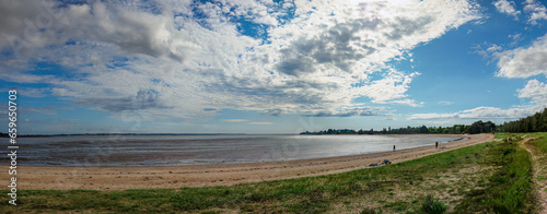 Panorama of a beach edge at low tide, cloudy sky, sand and grass. Penestain, Brittany, France.
