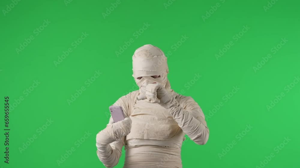 Green screen isolated chroma key video capturing a mummy typing on a smartphone, then showing it, revealing an advertising area, workspace mock up. Green screen isolated chroma key video capturing a mummy typing on a smartphone, then showing it, revealing an advertising area, workspace mock up.