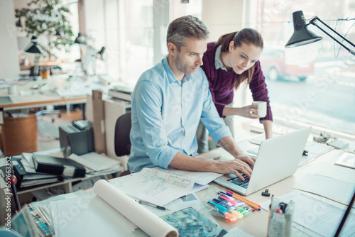 Young man and woman using the laptop while working together on a project in a startup company office