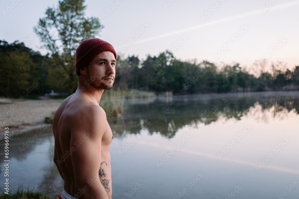Fototapeta premium Serious guy walking at the forest near the water and preparing for the swimming in the cold lake 