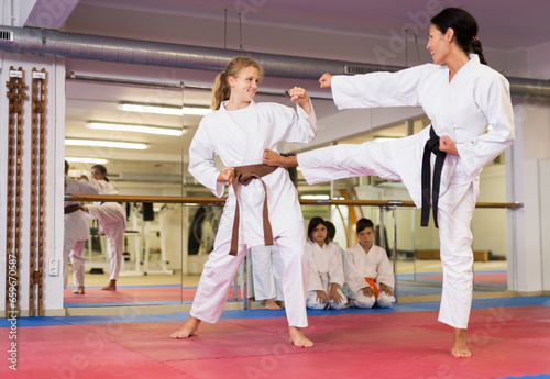 Concentrated teenager girl with her coach practicing self-defense techniques in gym
